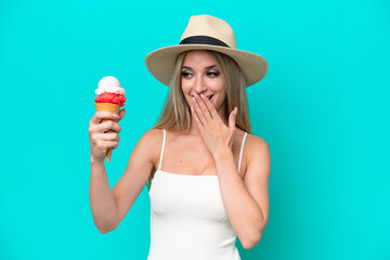 Blonde woman in swimsuit holding an ice cream isolated on blue background with surprise and shocked facial expression