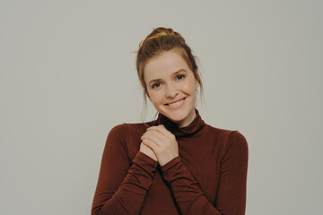 Grateful thankful young woman holding folded hands on chest, expressing gratitude and thankfulness