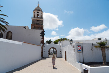 Una mujer con vestido y pelo rubio caminando hacia la iglesia de Teguise en Lanzarote, Isla...