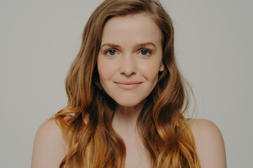 Naklejka premium Beauty shot of gorgeous caucasian female with healthy skin isolated on grey background