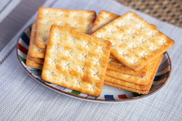 A pile of dry, thin crackers in a cup. Natural light.