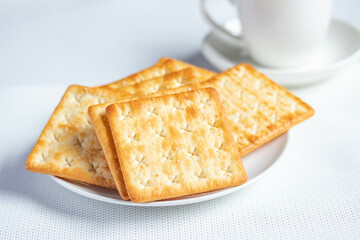 A pile of dry, thin crackers in a cup. Natural light.