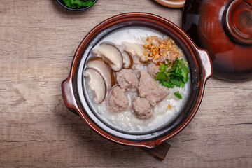 Pork porridge with shiitake mushrooms in brown cups topped with coriander and fried garlic