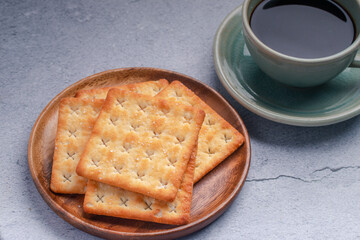 Hot black coffee in a green coffee cup with crackers.