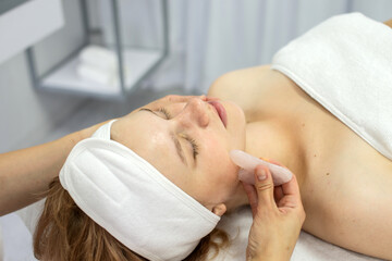 Fototapeta na wymiar Cosmetologist does a facial massage with a set of gouache