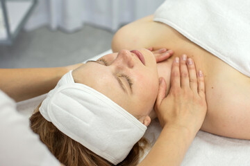 A cosmetologist massages the collar area. The girl is lying with her eyes closed