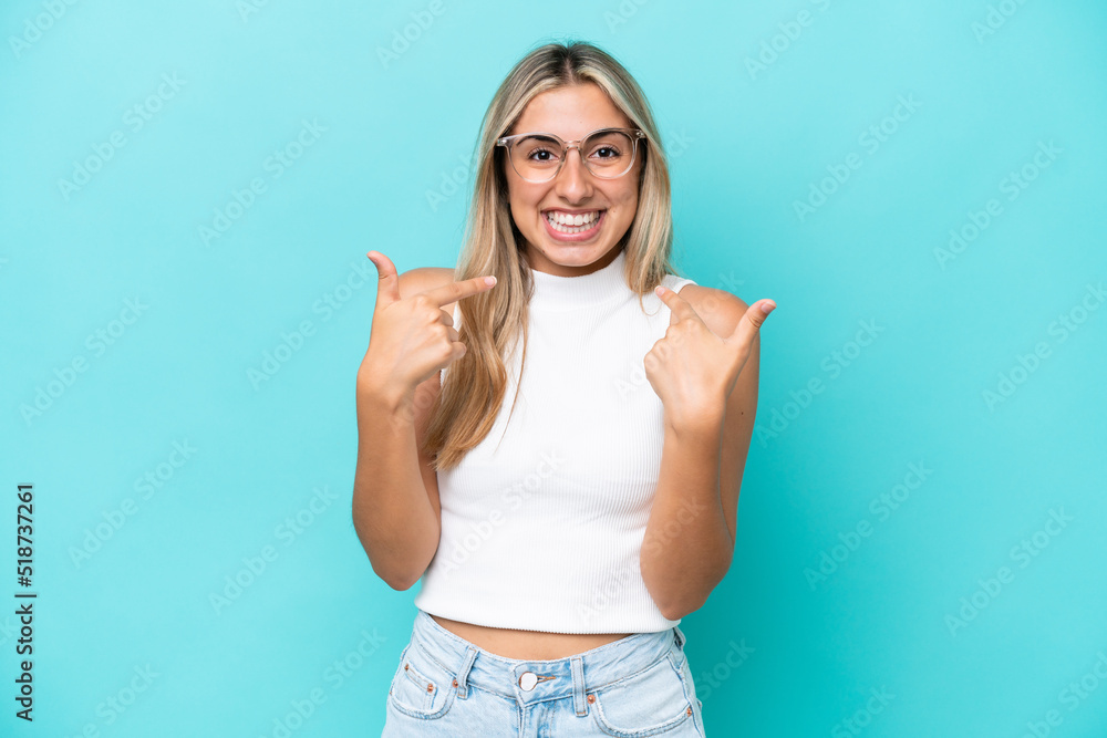 Wall mural Young caucasian woman isolated on blue background with surprise facial expression