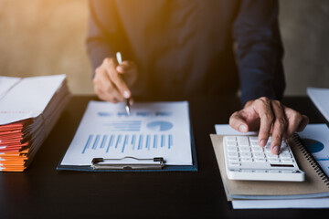 Fototapeta premium Close up of hands working and calculating on financial and accounting graft and chart in office space.