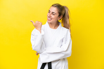 Young caucasian woman doing karate isolated on yellow background pointing to the side to present a...