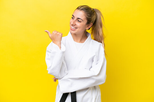 Young caucasian woman doing karate isolated on yellow background pointing to the side to present a product