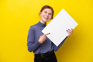 Young English woman isolated on yellow background holding an empty placard with happy expression...