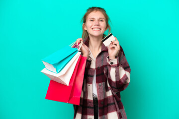 Young English woman isolated on blue background holding shopping bags and a credit card