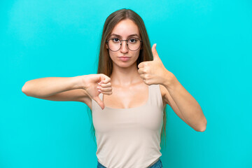 Fototapeta premium Young caucasian woman isolated on blue background making good-bad sign. Undecided between yes or not