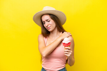 Young caucasian with a cornet ice cream isolated on yellow background suffering from pain in shoulder for having made an effort