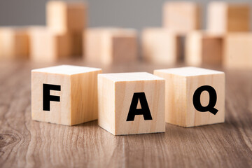 Frequently asked question concept. Wooden blocks with word FAQ on wooden background.