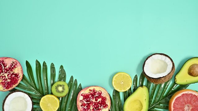  Summer composition with natural palm leaves and exotic fruits on cyan background. Stop motion flat lay. Copy space