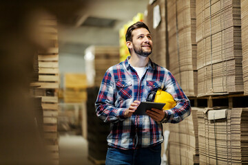 A paper and cardboard industry worker with tablet in hands inventorying in storage.