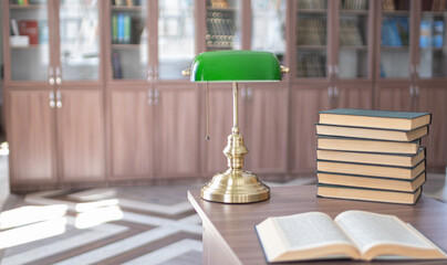Book stack on wood desk and blurred bookshelf in the library room. Table with books and open textbook. Stack of books in library. education background, back to school concept, Library theme
