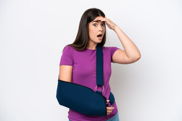 Young Brazilian woman with broken arm and wearing a sling isolated on white background doing...