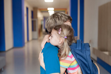 Upset schoolchild hugging father. Stressed kid and parent. First day at school. Concept of back to...