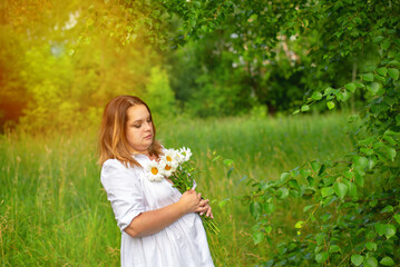 Portrait of a beautiful girl in a white dress in the park on a summer day.