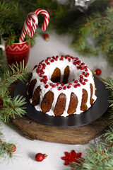 Christmas food. Round pie with white icing. Cupcake with a hole in the middle with pomegranate. Green spruce branches on the table. Still life. Sweet pastries, desserts and treats for the new year.