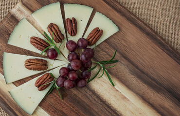 Assorted cheeses with grapes, nuts, Goat cheese. wooden board.