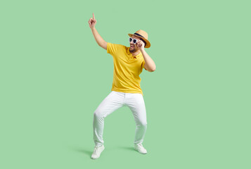 Cheerful funny man in good mood having fun dancing isolated on light green background. Caucasian young man in summer casual clothes jokingly fooling around and laughing at party. Banner. Full length.