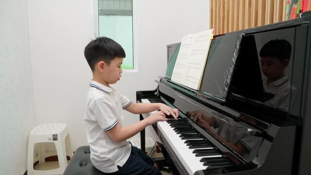 Asia boy in shirt playing piano in the classroom at school. Examination to get upper level. Education, skill and learning concept. Musician piano practice. New normal for online exam