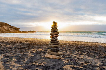 Fototapeta na wymiar Stack of Stones Balance on a Beach Against a Cloudy Sky at Sunset Time.Zen Concept.Copy Space