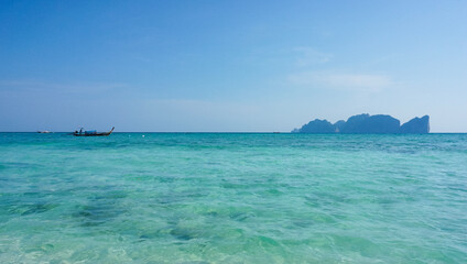 Tropical seascape with a long-tail boat, island, turquoise water and blue sky, Koh Phi Phi, Thailand