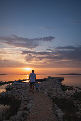 Father and little son by the sea during the sunset on island pag in croatia - obrazy, fototapety, plakaty