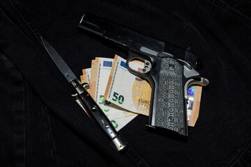 An Italian knife, a pile of banknotes and a pistol with a decorative grip