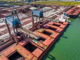 Fototapeta na wymiar Bulk Carrier Ship Offloading Cargo By Crane for Processing