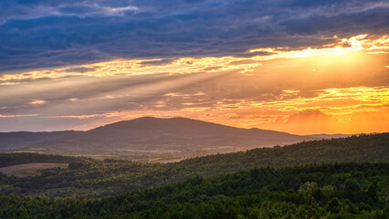 Mountain forests in the light of sunbeams and cloudy sky