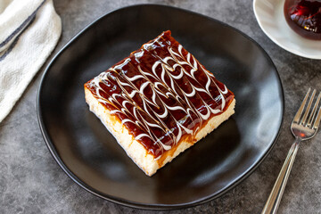 Trilece dessert. Slice of dessert with caramel and milk on a dark background. Bakery products. side view. Close-up.