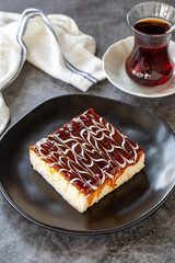 Trilece dessert. Slice of dessert with caramel and milk on a dark background. Bakery products. Vertical view. Close-up.