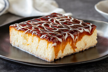 Trilece dessert. Slice of dessert with caramel and milk on a dark background. Bakery products. side view. Close-up.