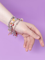 Three small silver charm bracelets with many charms. Purple background. Creating jewelry. Children's bracelets