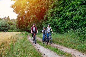 Naklejka premium family riding a bike in the countryside at hot sunny day