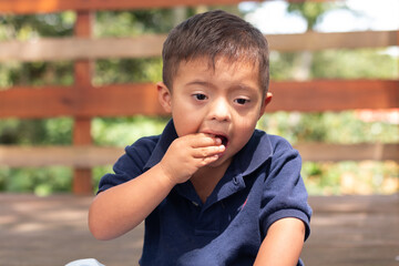 Portrait of a child with Down syndrome who eats candy in a peculiar way.