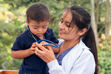 Doctor holding in her arms a child with Down syndrome to whom she lent her stethoscope.