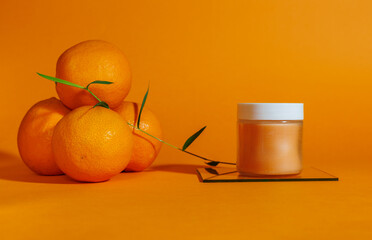 jar of lotion or balm with oranges on orange background