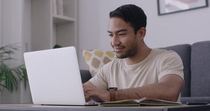 Male blogger feeling inspired while thinking of ideas and content to use for an article. Happy freelancer writing a story or letter for job application. Man typing on laptop while sitting at home.