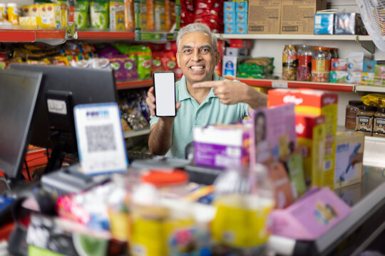 Portrait of happy man showing mobile phone screen at supermarket
