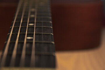 The neck of an acoustic six-string guitar. Macro. Place for text.