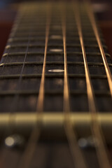 The neck of an acoustic six-string guitar. Close up. Vertical.