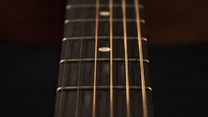The neck of an acoustic six-string guitar. Close up.