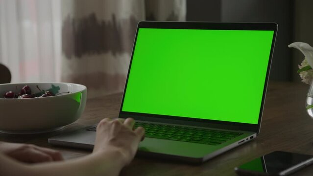 Close up of a caucasian woman hand rest on a laptop computer touchpad with green screen chroma key