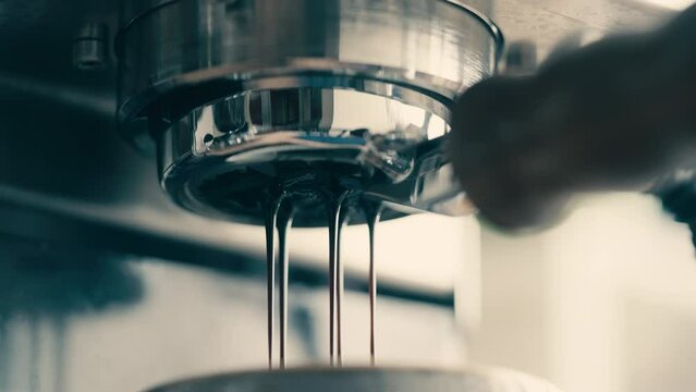 Macro shot of coffee pouring from bottomless filter holder, coffee preparationClose-up of aromatic drink pouring into a cup